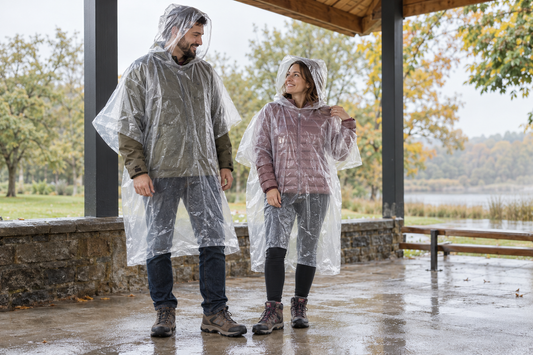Zwei unterschiedlich große Erwachsene tragen transparente Regenponchos über ihren Jacken.