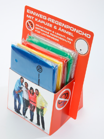 Studioaufnahme eines Verkaufsdisplays mit bunten Einweg-Regenponchos in Blau, Gelb, Rot und Grün – mit Aufdruck „Mit Kapuze & Ärmeln“ und einer fröhlichen Gruppe auf der Vorderseite.